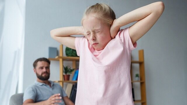 パパに怒られ耳をふさぐ女の子の写真