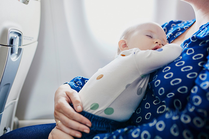 飛行機でママに抱かれ眠るこども